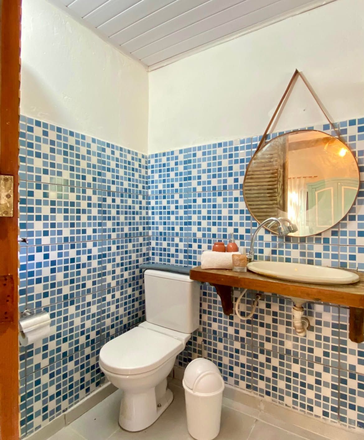 Banheiro com azulejos azuis e espelho redondo