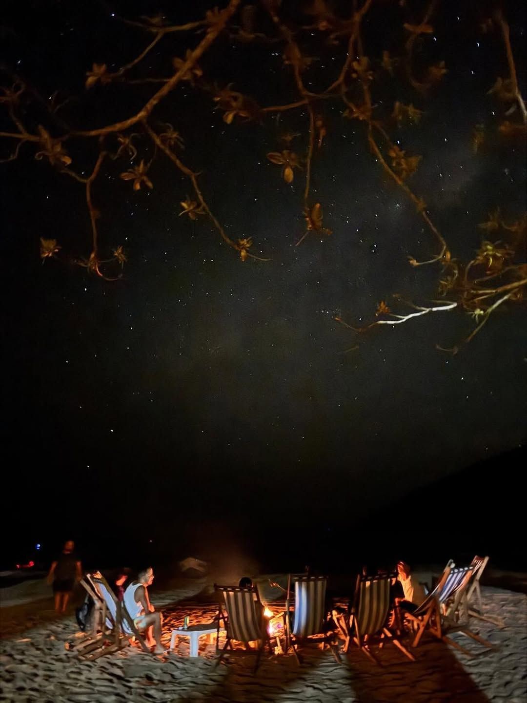 Fogueira com cadeiras de praia sob o céu estrelado