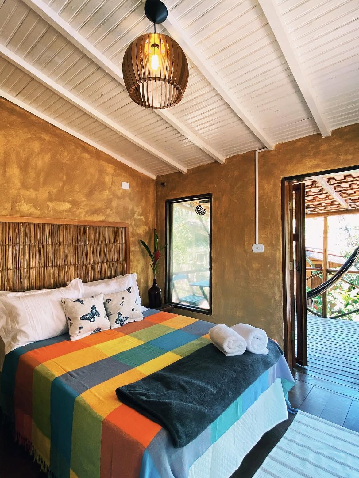 Quarto de casal com paredes de barro e porta para a varanda